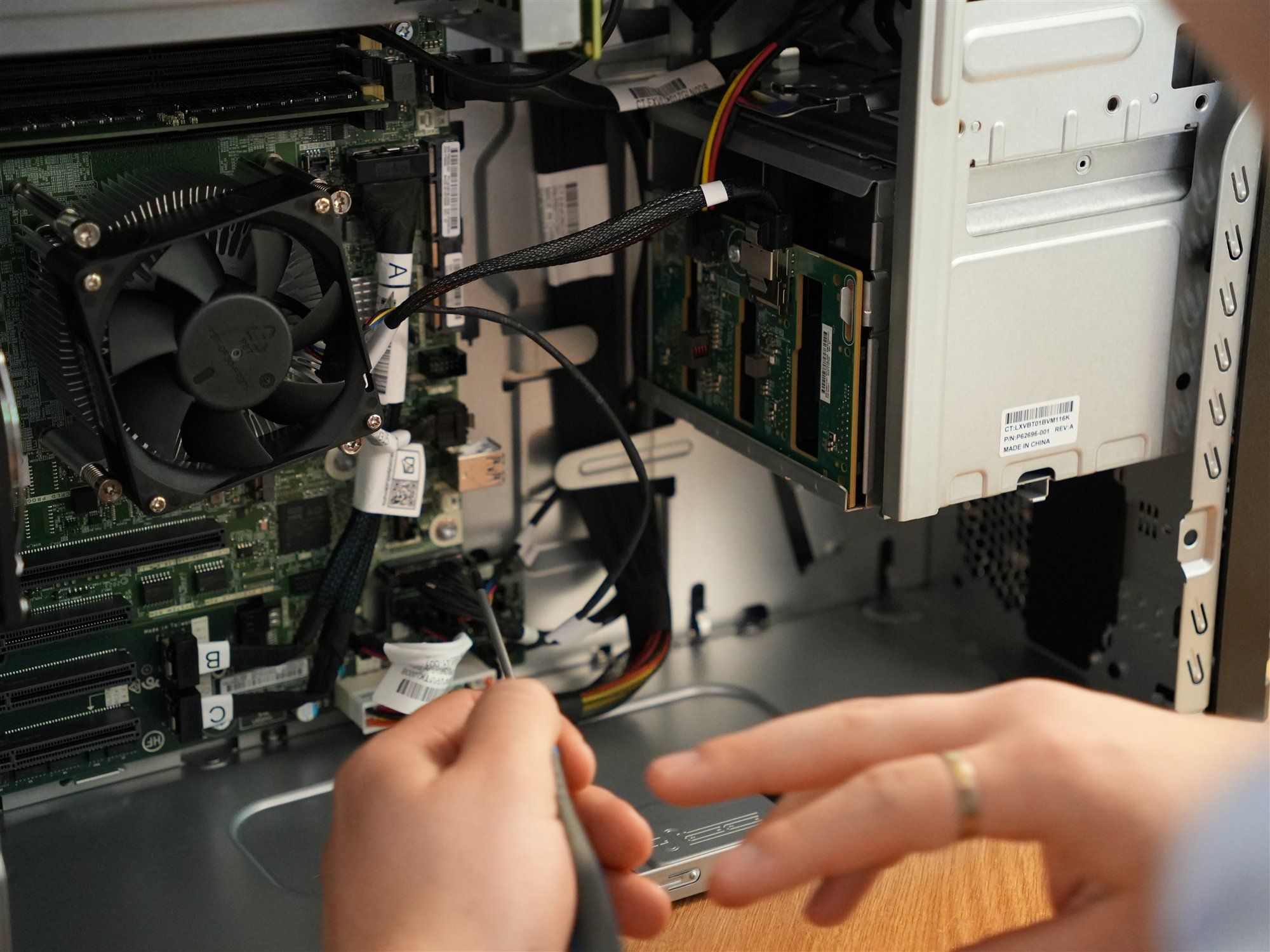 Hände eines Holzer-Technikers mit Schraubendreher an der Hauptplatine eines geöffneten Computers