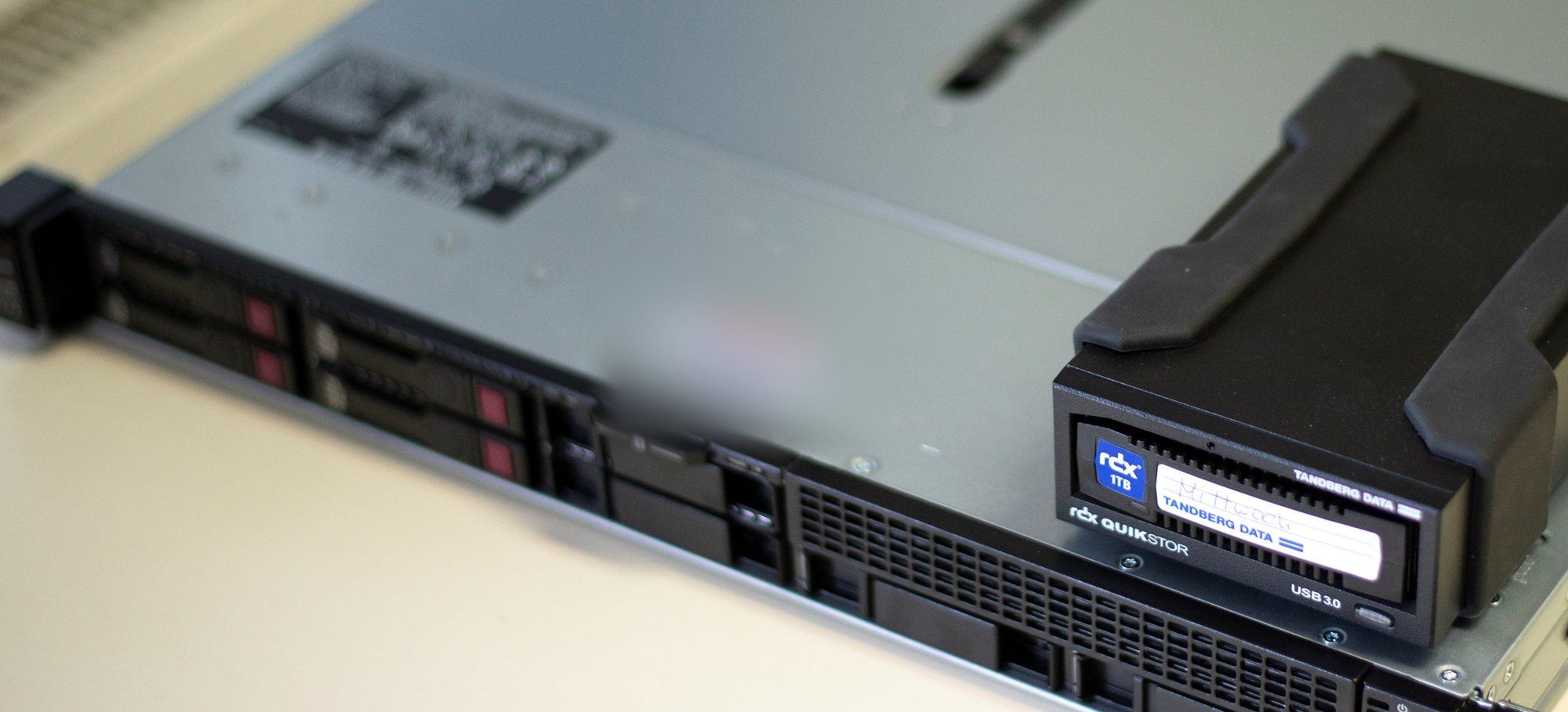 Flacher Rack-Server auf einem Tisch, darauf ein angeschlossenes RDX-Laufwerk für die Datensicherung