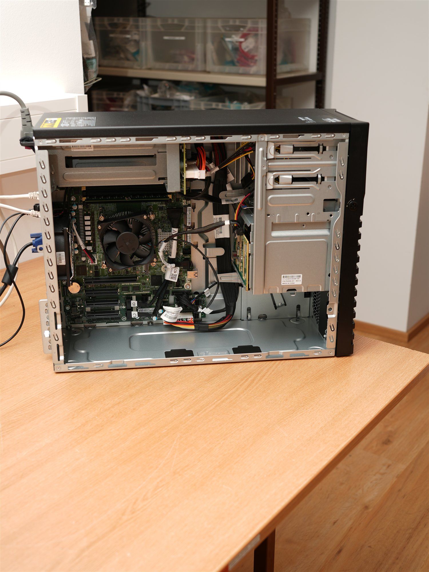 Geöffneter Tower-Server mit Hauptplatine, Laufwerkskäfig und Kabeln auf einem Holztisch