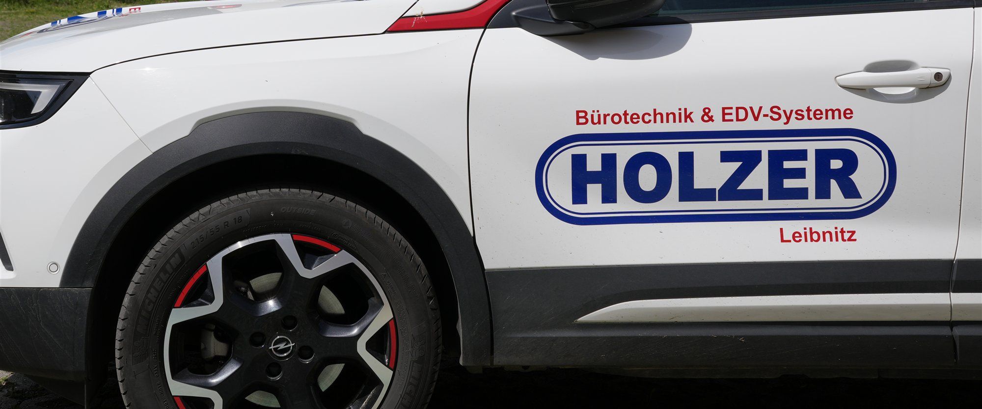 Holzer-Logo mit den Aufschriften Bürotechnik & EDV-Systeme und Leibnitz auf der Tür eines weißen Firmenwagens